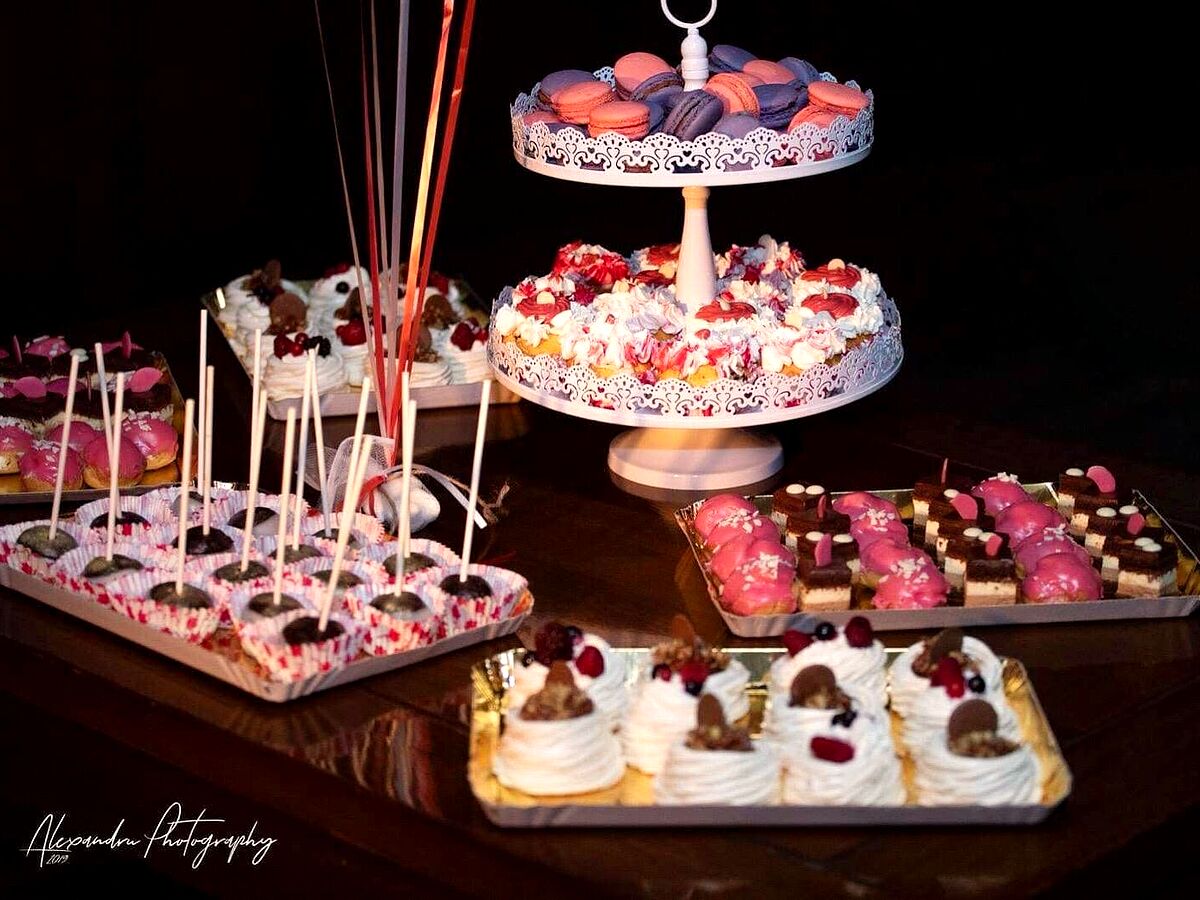 Masă de dulciuri cu macarons, mini-tarte, bezele și prăjituri mici