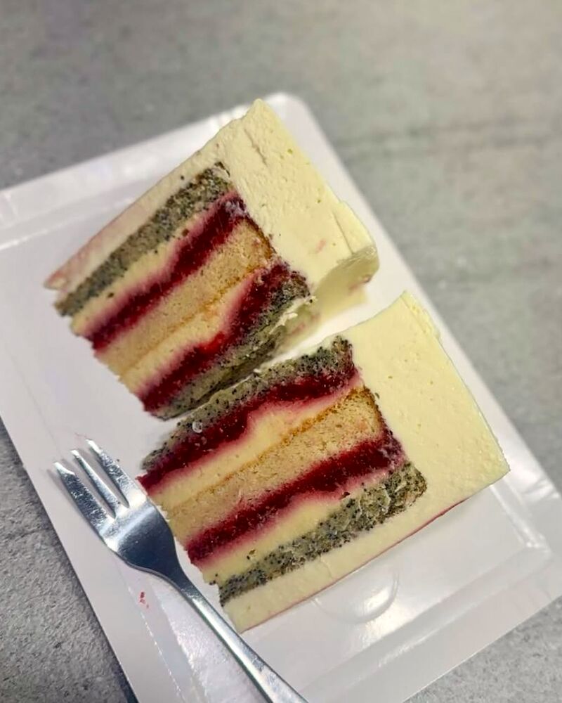 Felie de tort cu cremă de fistic și fructe roșii, servită pe farfurie