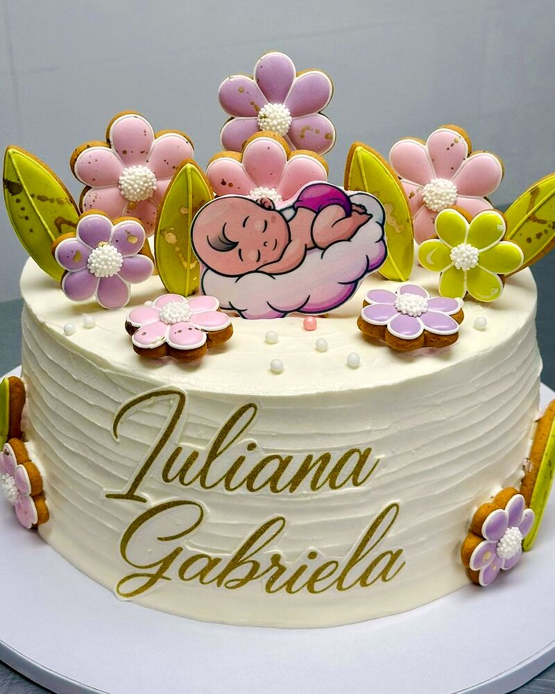 Tort alb de botez cu figurină de bebeluș adormit și flori de zahăr colorate