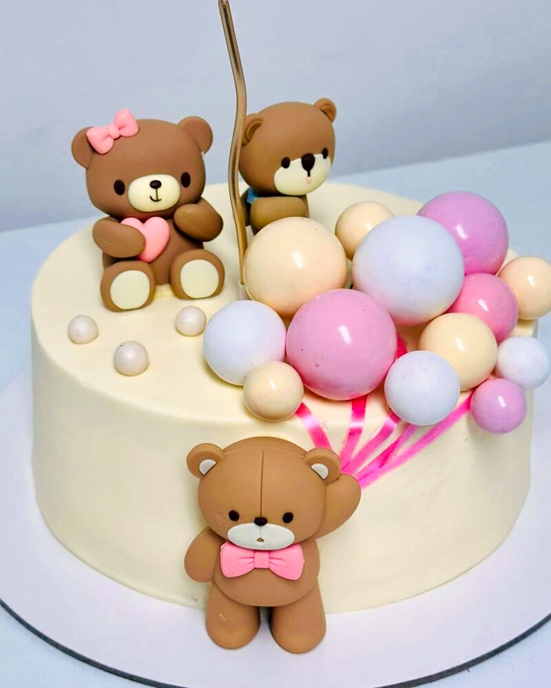 Tort alb cu doi ursuleți de zahăr și baloane pastel